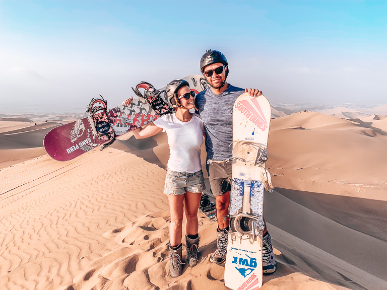 Ashley and Chris standing at the top of a dune getting ready to do some Sandboarding