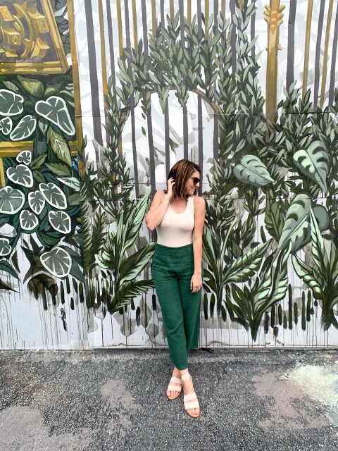 Leaning against a wall covered in painted greenery.