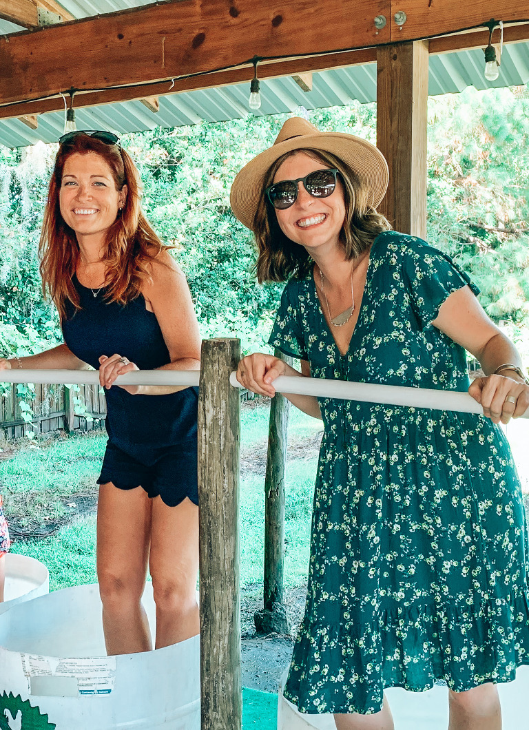 Ashley & Dani smiling while they stomp on the grape and other fruits in their buckets.