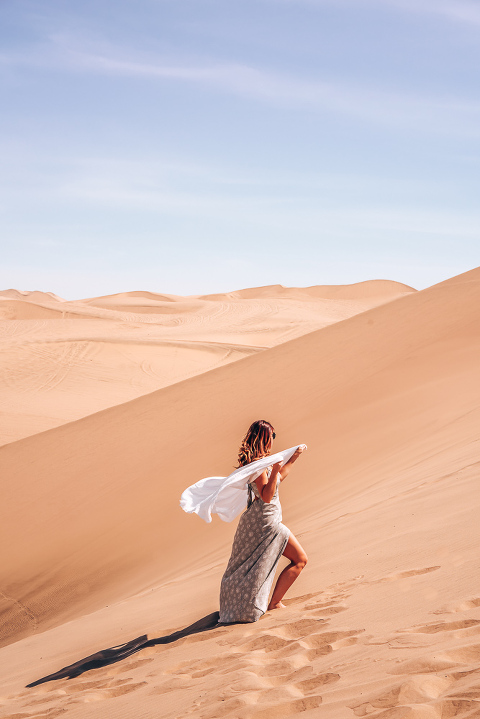 Ashley standing in the Huacachina Dessert surrounded by beautiful golden sands