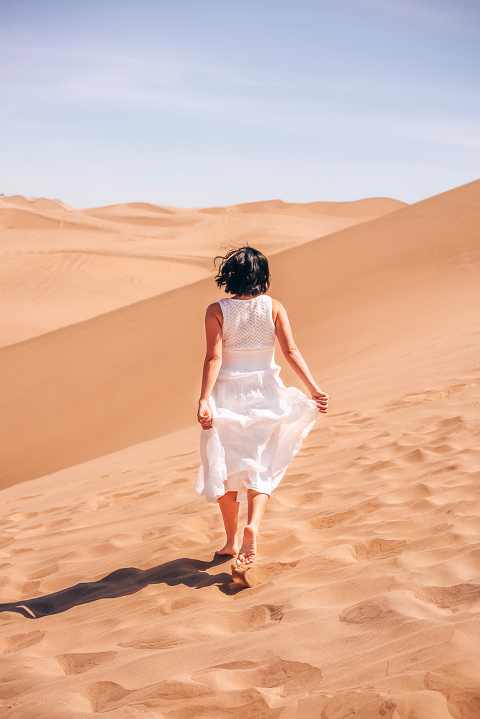 Dani Running through the sand in the Huacachina Dessert surrounded by beautiful golden sands and blue skies